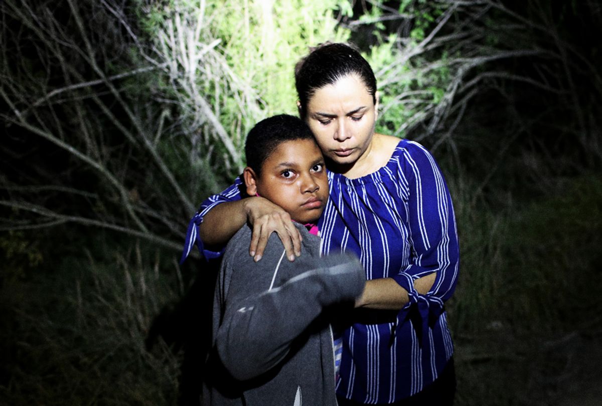 A U.S. Border Patrol spotlight shines on a terrified mother and son from Honduras as they are found in the dark near the U.S.-Mexico border in McAllen, Texas.  (Getty/John Moore)