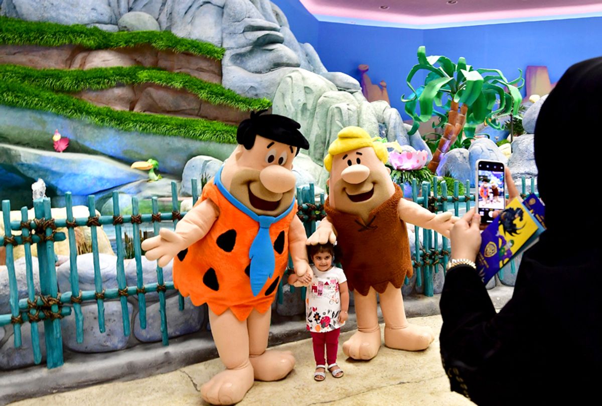 Employees wearing a Fred Flintstone and Barney Rubble costume pose for a picture with a girl at Warner Bros. World, the first-ever Warner branded indoor theme park, in the UAE capital Abu Dhabi on July 27, 2018. (Getty/Giuseppe Cacace)