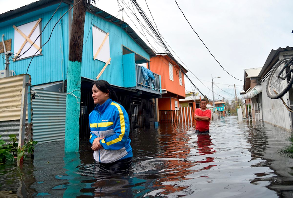 People walk across a flooded street in Juana Matos, Puerto Rico, on September 21, 2017 as the country faced dangerous flooding and an island-wide power outage following Hurricane Maria. (Getty/Hector Retamal)