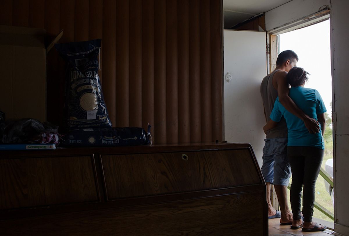 A farmworker couple, Nelson and Silvia* from Guatemala, surveys the flooding outside of their North Carolina trailer home after Hurricane Florence. (Justin Cook)