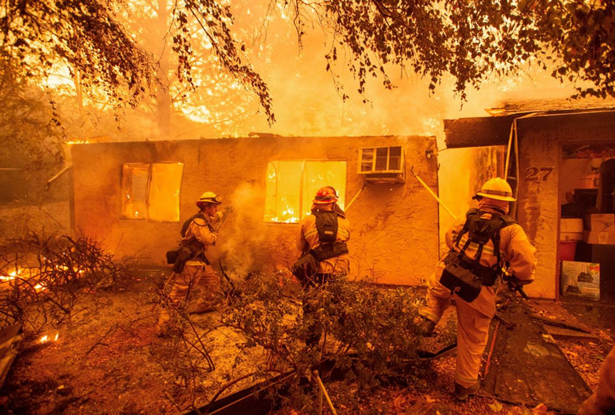 Firefighters push down a wall while battling against a burning apartment complex in Paradise, north of Sacramento, California on November 09, 2018 (Getty/Josh Edelson)