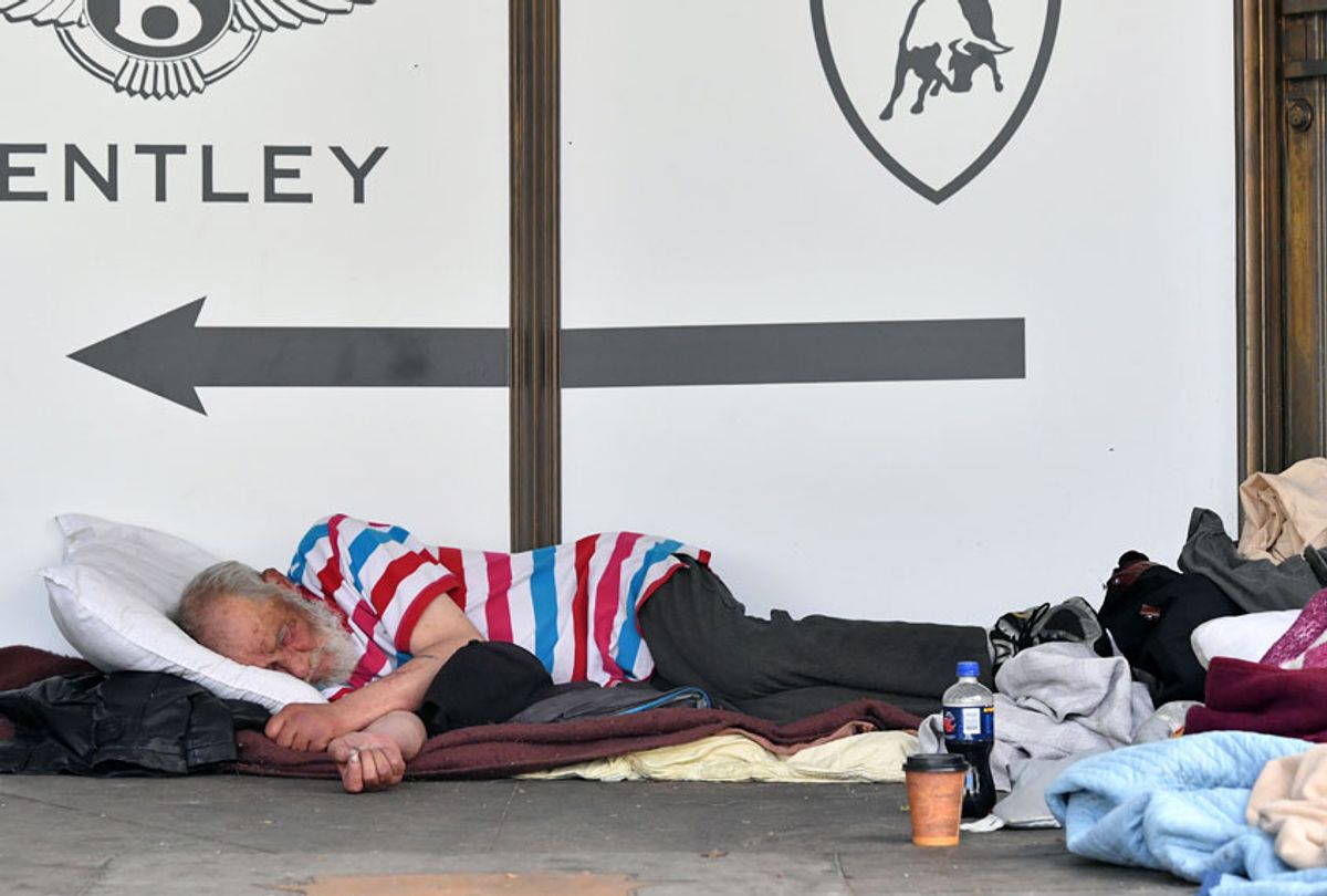 A homeless man sleeps in front of a luxury auto dealership in San Francisco, California on June, 10, 2016. (Getty/Josh Edelson)