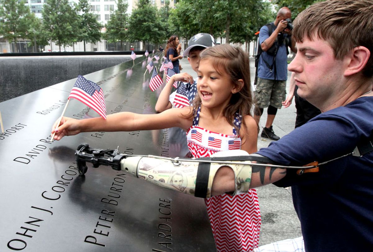 Retired Marine Sgt. John Peck, of Fredricksburg, Va., right, and Sophia Elwood, 7, the daughter of Peck's fiancee, place an American flag on one of the names inscribed at the south reflecting pool at the 9/11 Memorial in New York, July 4, 2014. (AP/Tina Fineberg)