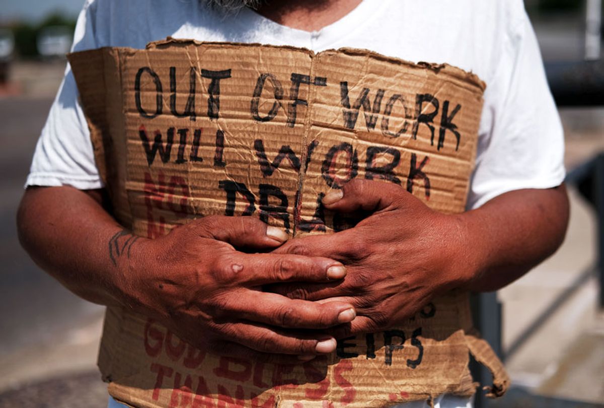 Unemployed man holding "OUT OF WORK" sign (Getty/Spencer Platt)