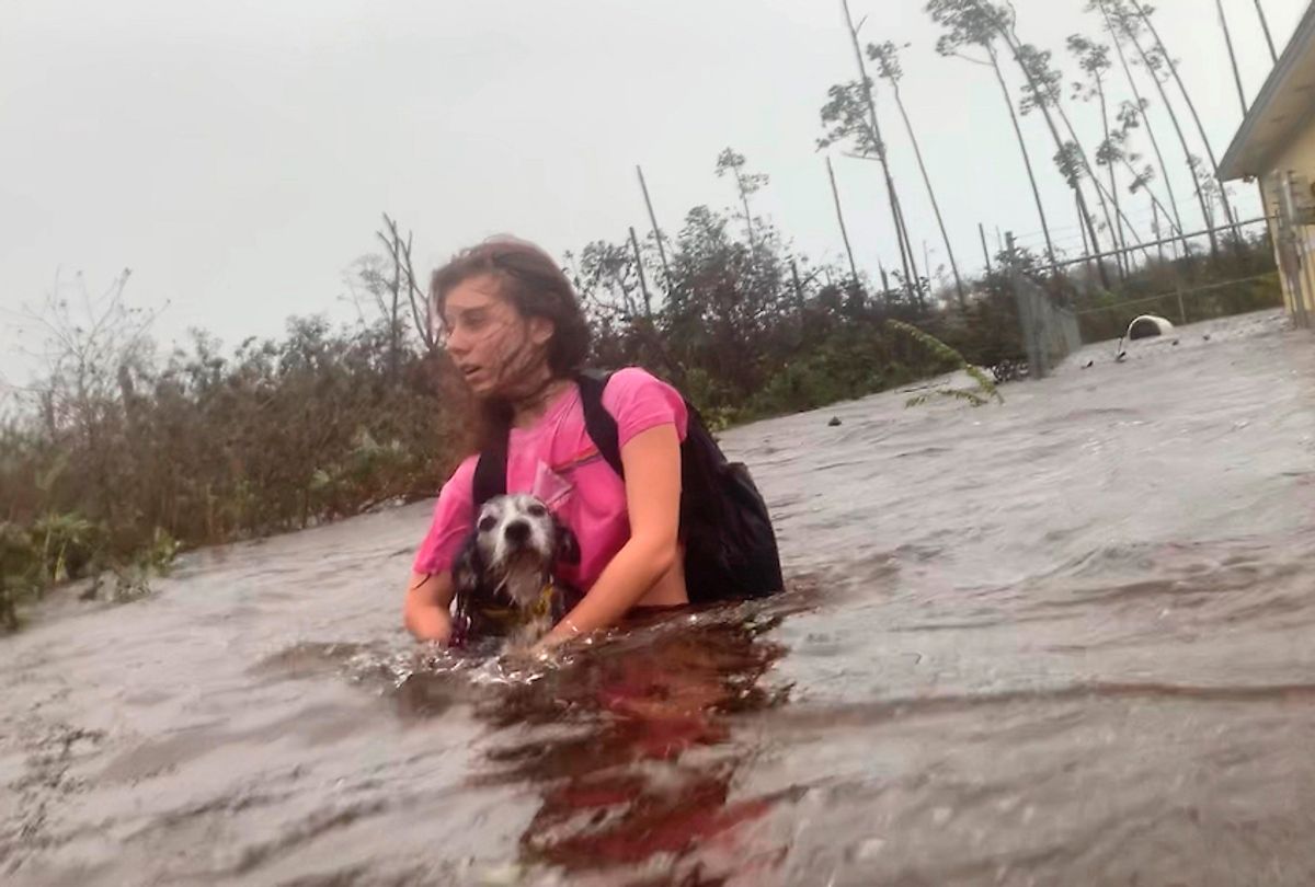 Julia Aylen wades through waist deep water carrying her pet dog as she is rescued from her flooded home during Hurricane Dorian in Freeport, Bahamas, Tuesday, Sept. 3, 2019.  (AP Photo/Tim Aylen)