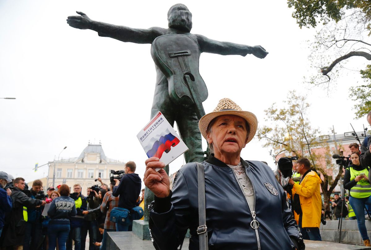 An opposition activist holds the Russian Constitution book in front of the monument to Soviet-era opposition legendary bard Vladimir Vysotsky during a protest in the center of Moscow, Russia, Saturday, Aug. 17, 2019.  (AP Photo/Alexander Zemlianichenko)