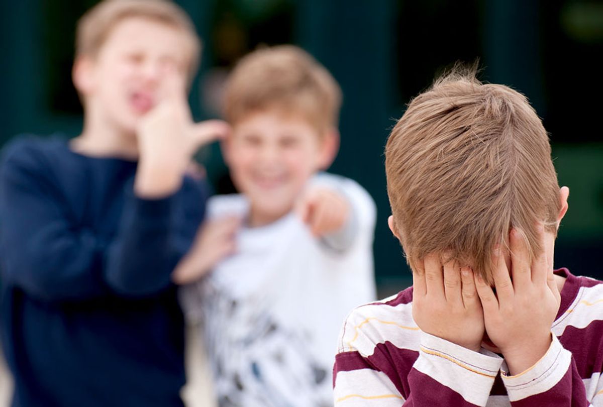 An upset elementary school boy hides his face while being bullied by two other boys. Shot in front of their elementary school. (Getty/ Brycia James)