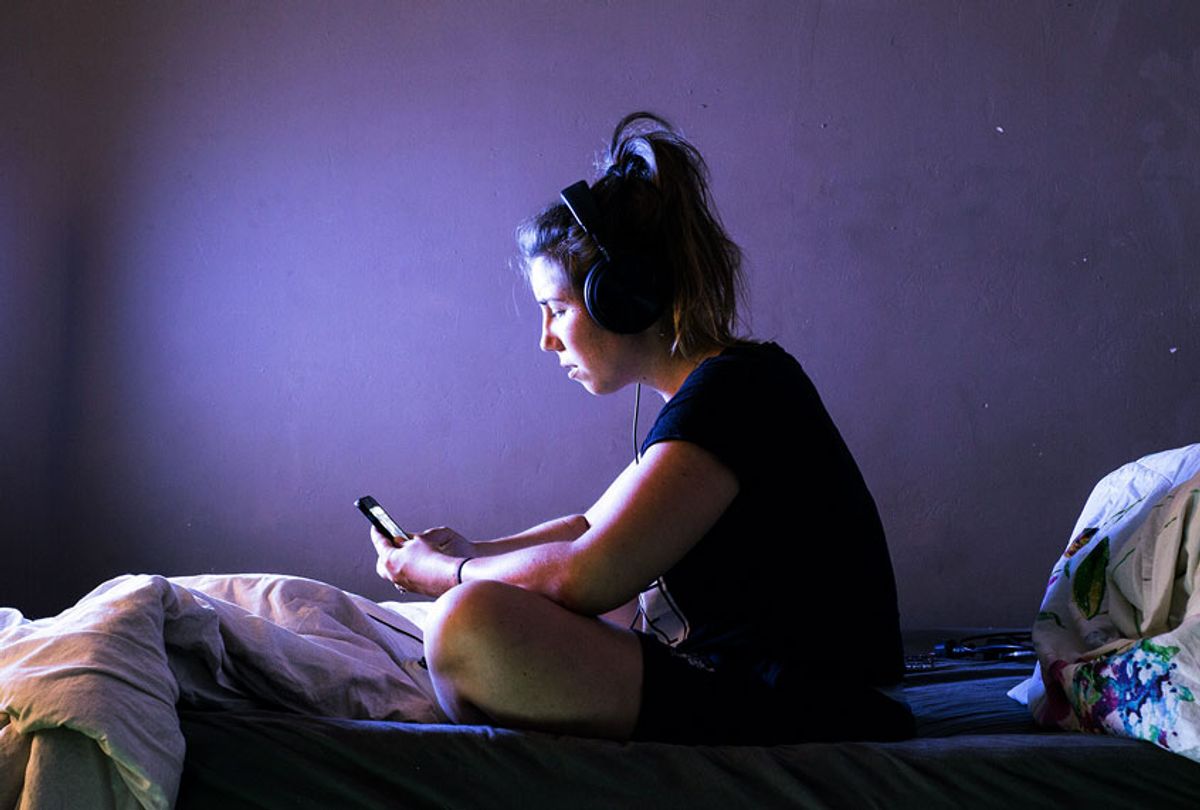 Young woman on her phone in bed at night (Getty Images/Cerro Photography)
