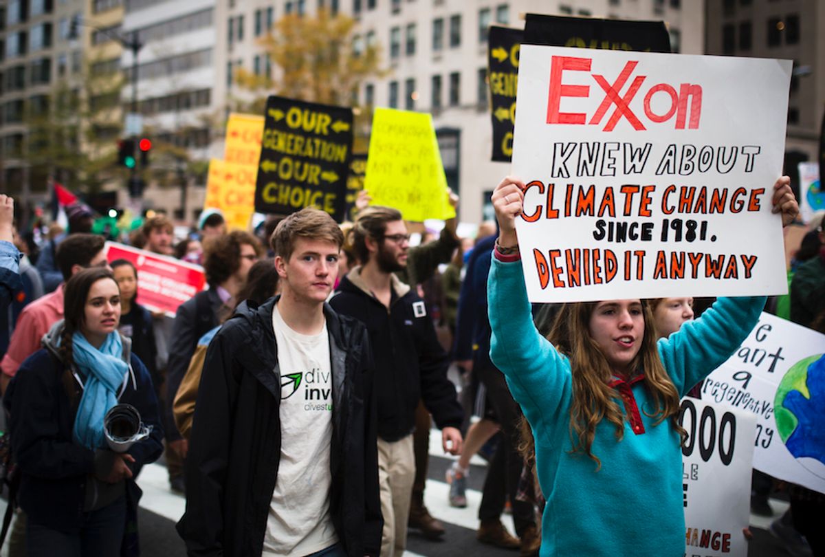 Climate activists demonstrate in Washington, D.C. in 2015. One displays a sign admonishing ExxonMobil for its complicity in furthering the climate apocalypse. (Johnny Silvercloud/Flickr)