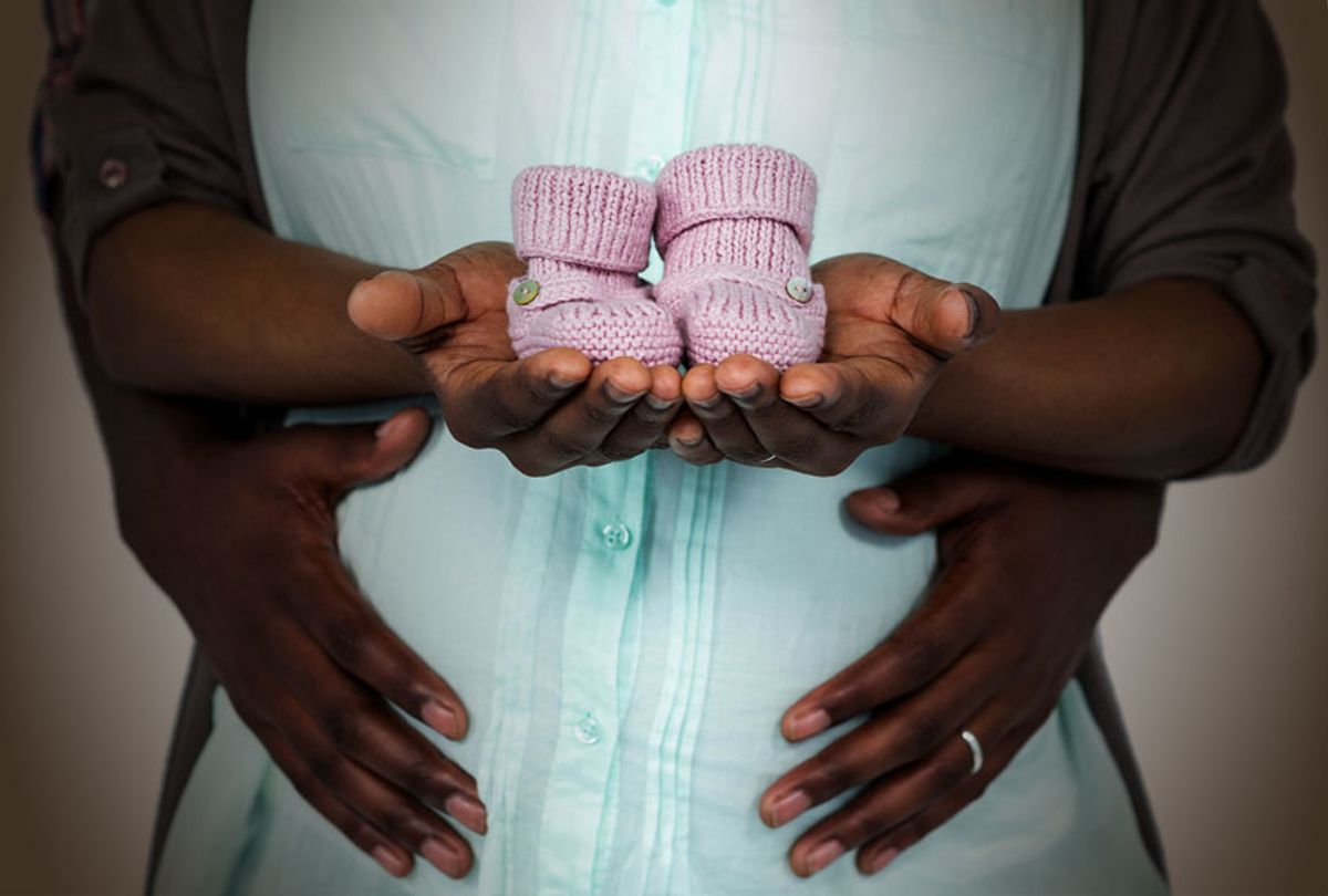 Pregnant couple holding baby shoes  (Getty Images/Salon)