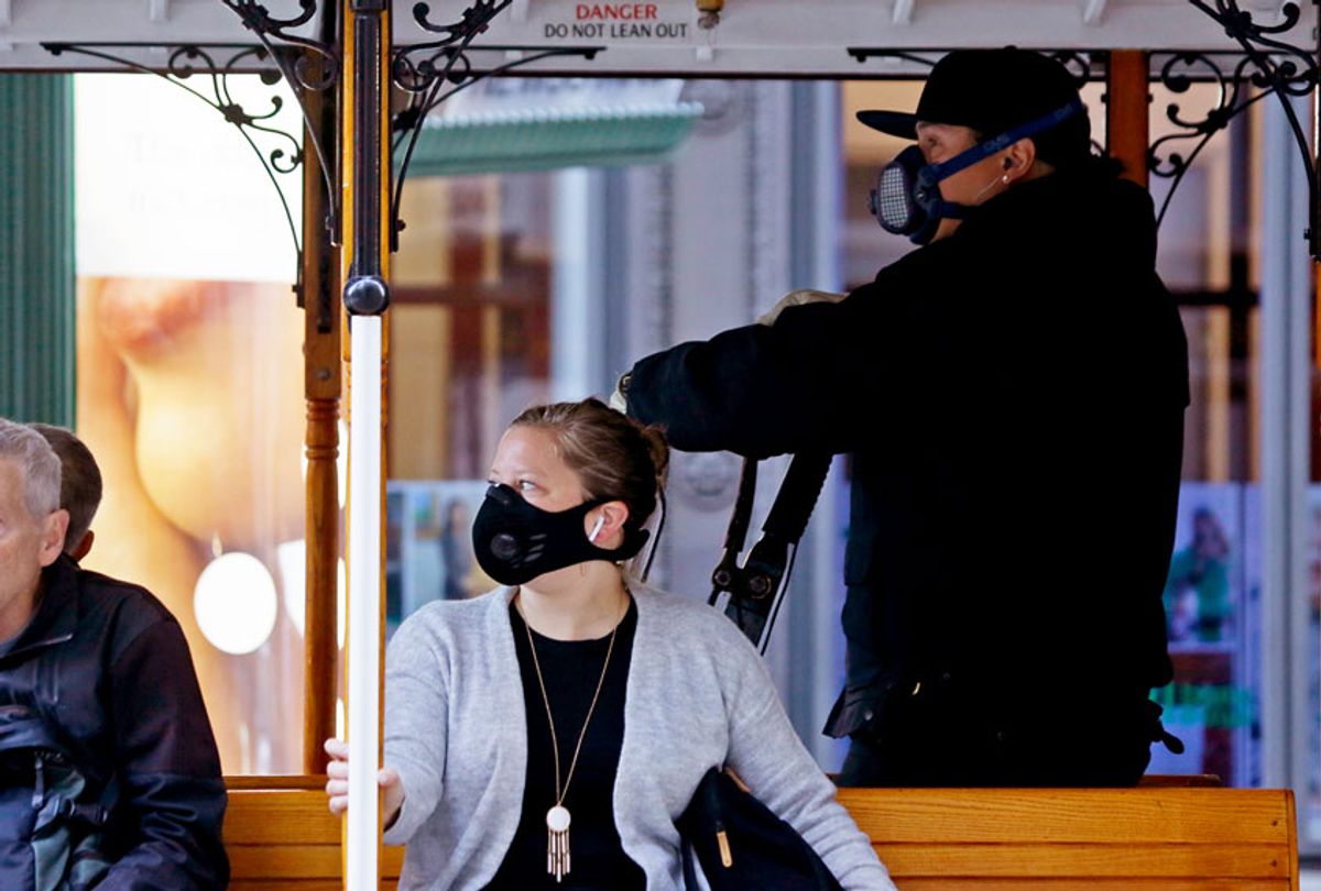 A California Street cable car operator and passenger wear breathing masks to protect against smoke from wildfires Monday, Oct. 28, 2019, in San Francisco. A wildfire that has been burning in Northern California's wine country since last week grew overnight as nearly 200,000 people remain under evacuation orders. (AP Photo/Eric Risberg)