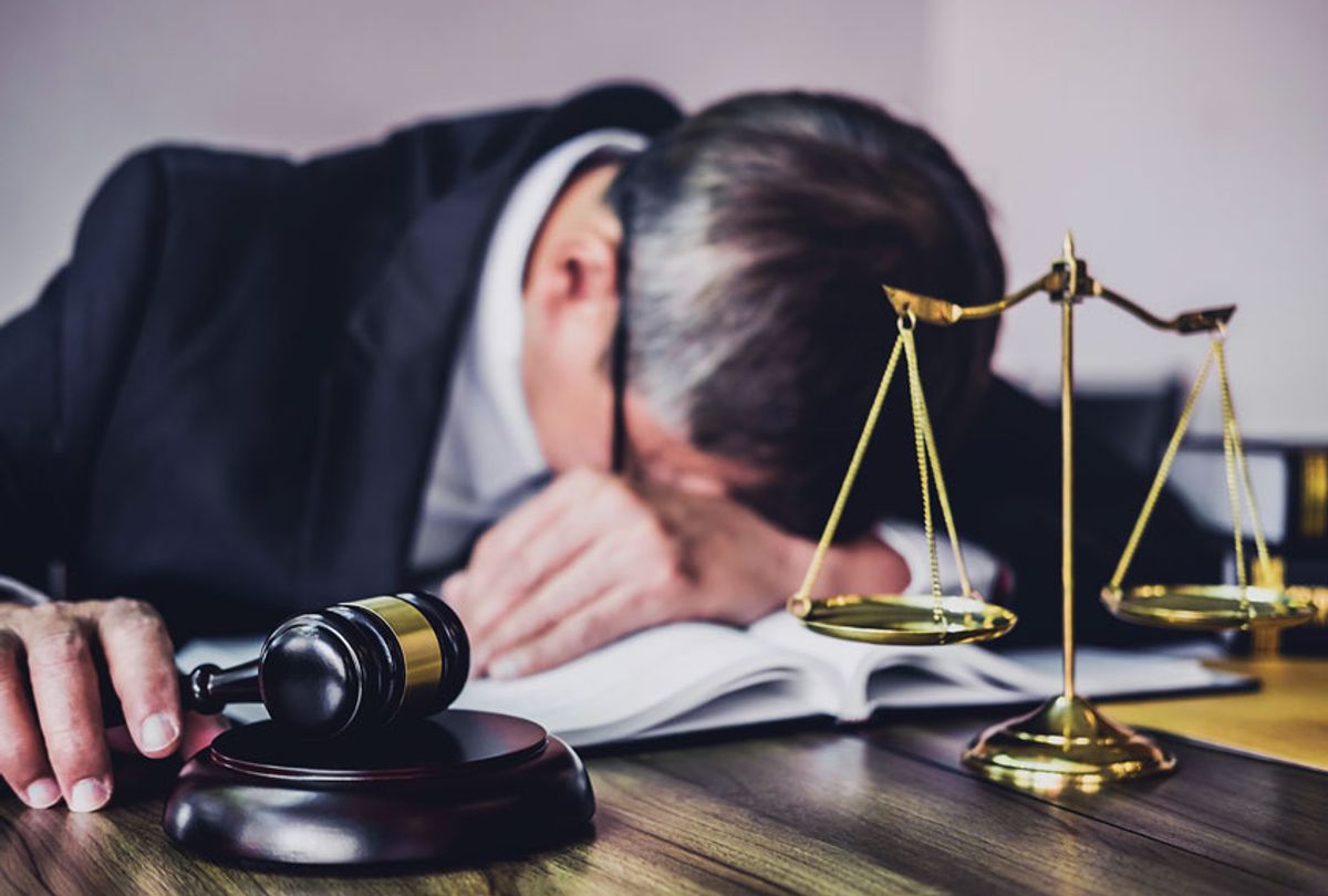 Tired lawyer with law-book, scales, and gavel (Getty Images)