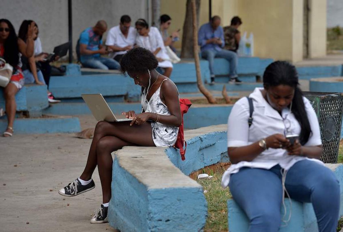 People use their mobile phones and laptops to connect to internet through WiFi at a park in Havana, on December 5, 2018. (Yamil Lage/AFP via Getty)