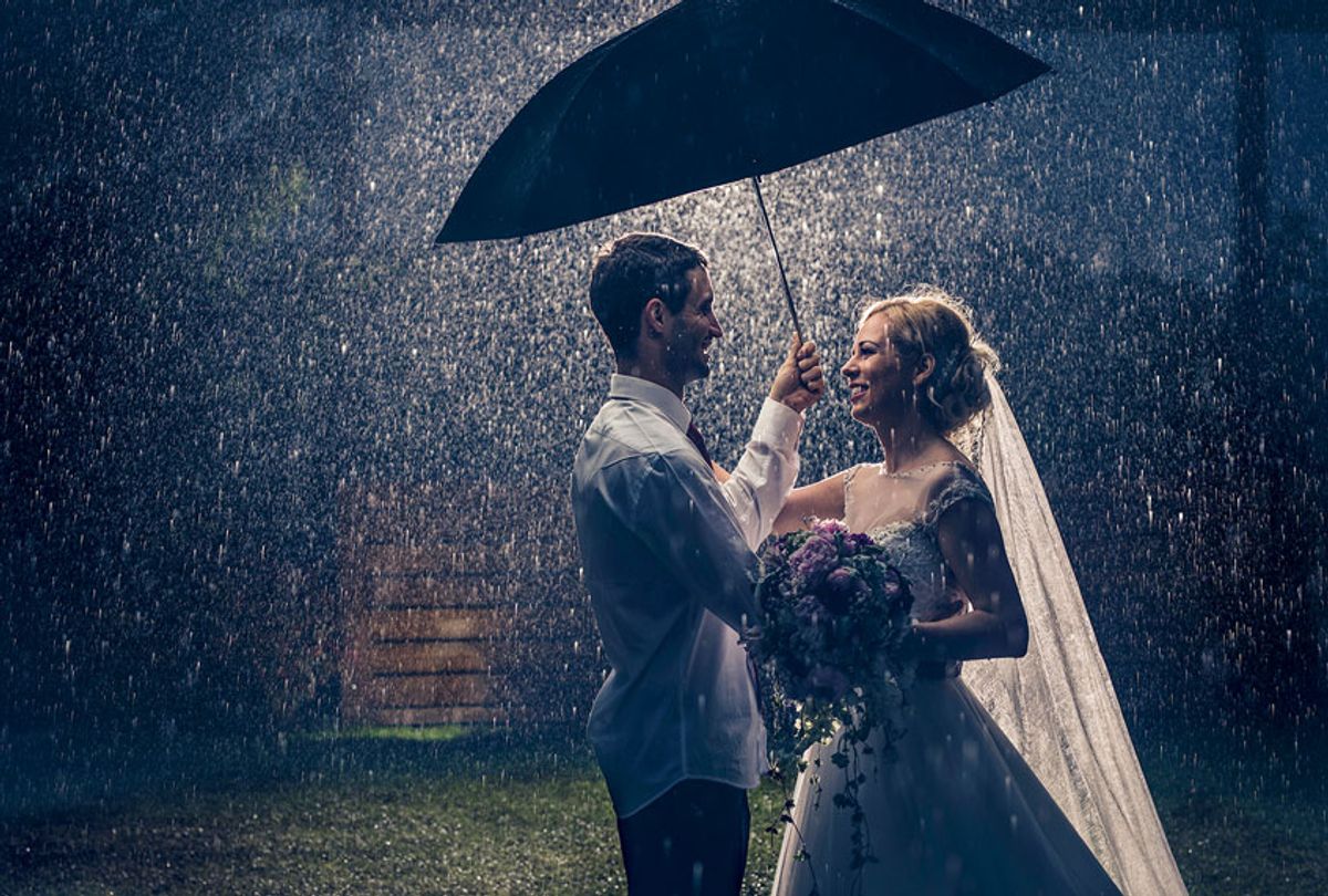 Loving bride and groom looking at each other and communicating while standing on a rain and protecting themselves with an umbrella. (Getty Images)