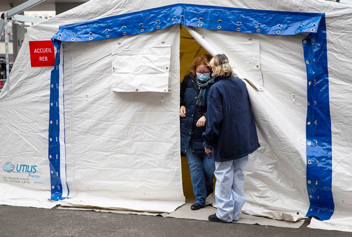 A nurse escorts a patient with covid-19 symptoms to a tent set up in a courtyard of the Henri Mondor Hospital in Creteil, near Paris, on March 6, 2020, to take blood sample as the novel coronavirus strain that erupted in China this year and causes the COVID-19 disease already left nine dead in France and made hundreds ill.  (HOMAS SAMSON/AFP via Getty Images)