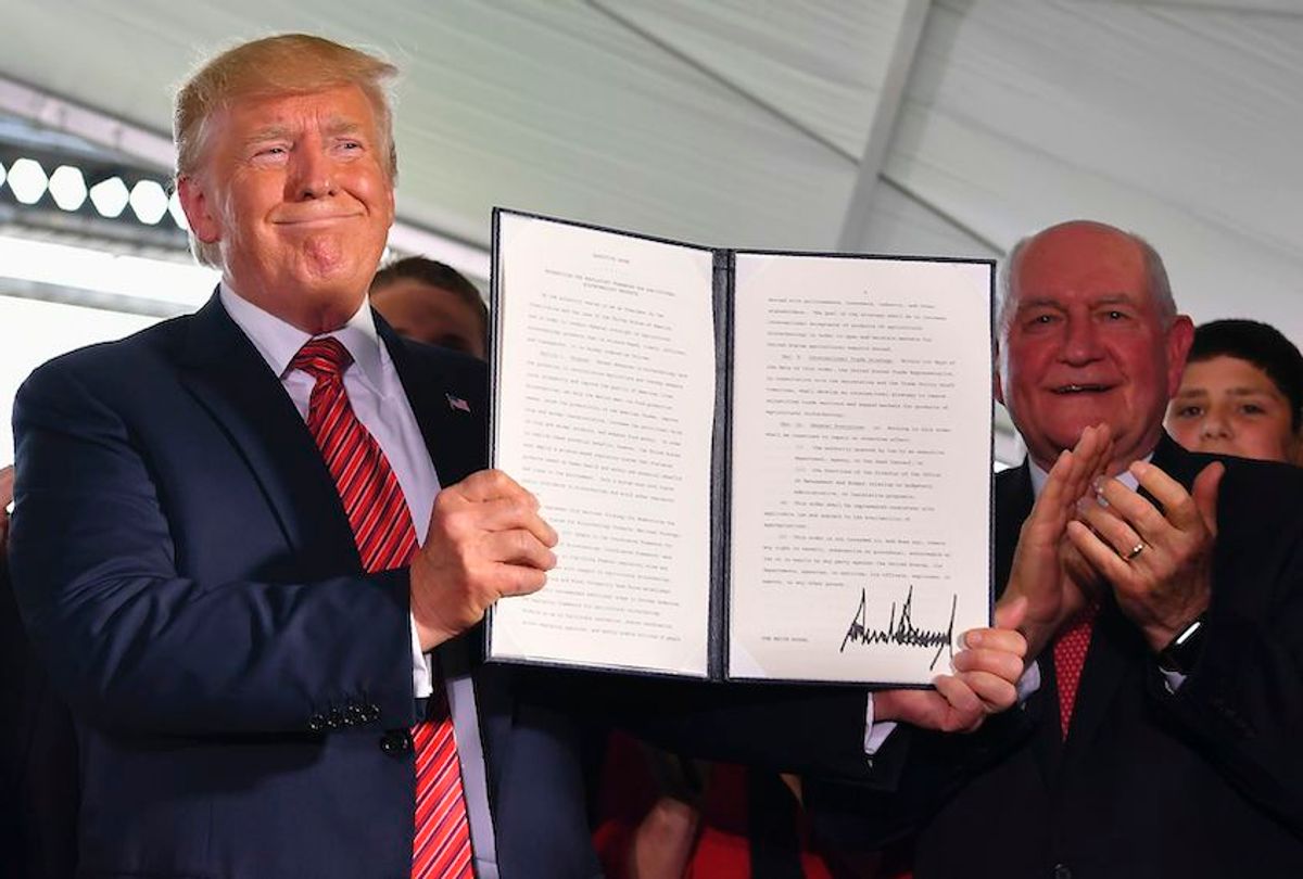 President Donald Trump holds up an executive order to streamline the approval process for GMO crops, as Secretary of Agriculture Sonny Perdue (R) claps following a speech by the president at the Southwest Iowa Renewable Energy ethanol plant in Council Bluffs, Iowa on June 11, 2019. (Mandel Ngan/AFP via Getty)
