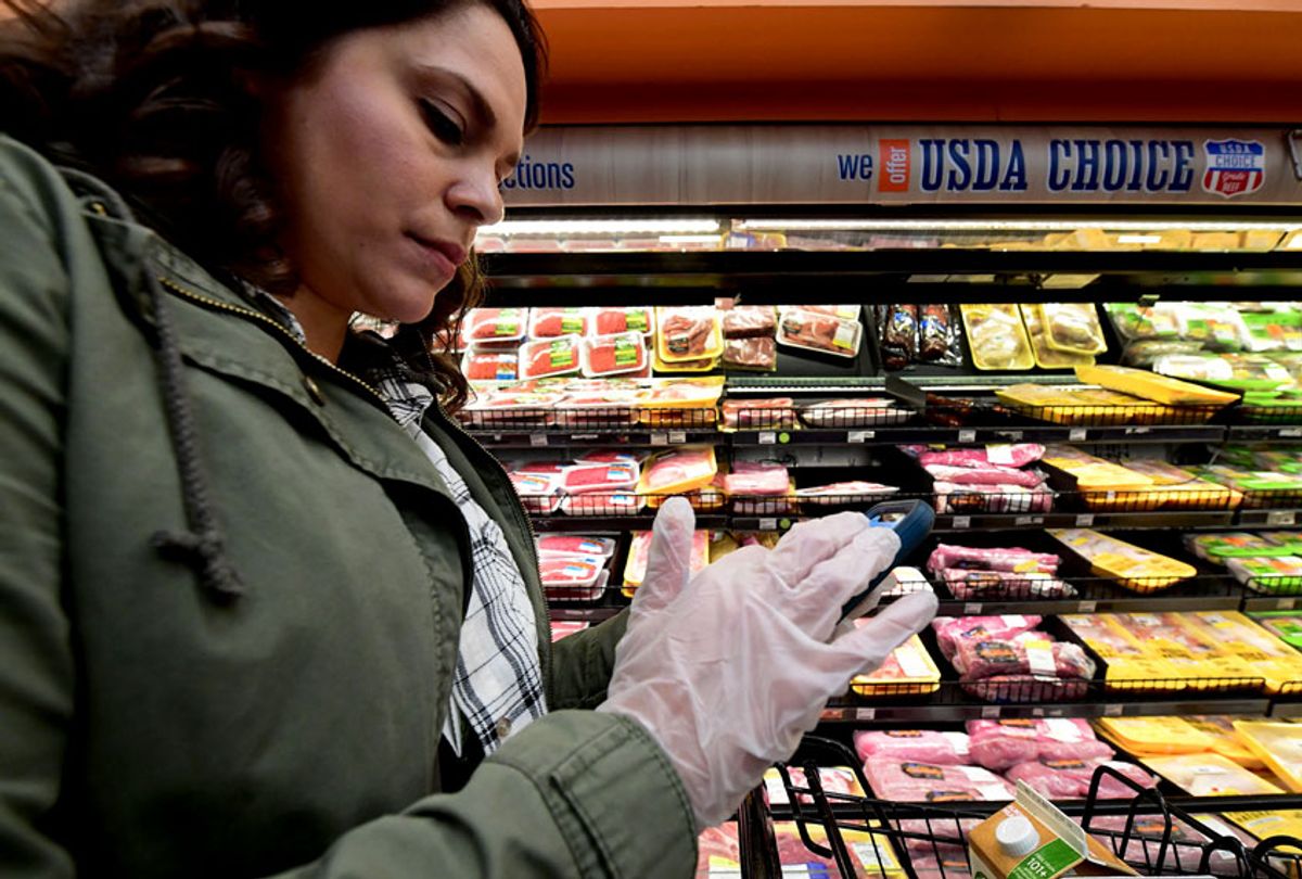 Instacart employee Monica Ortega wears gloves while using her cellphone to check orders while picking up groceries from a supermarket for delivery on March 19, 2020 in North Hollywood, California. (FREDERIC J. BROWN/AFP via Getty Images)