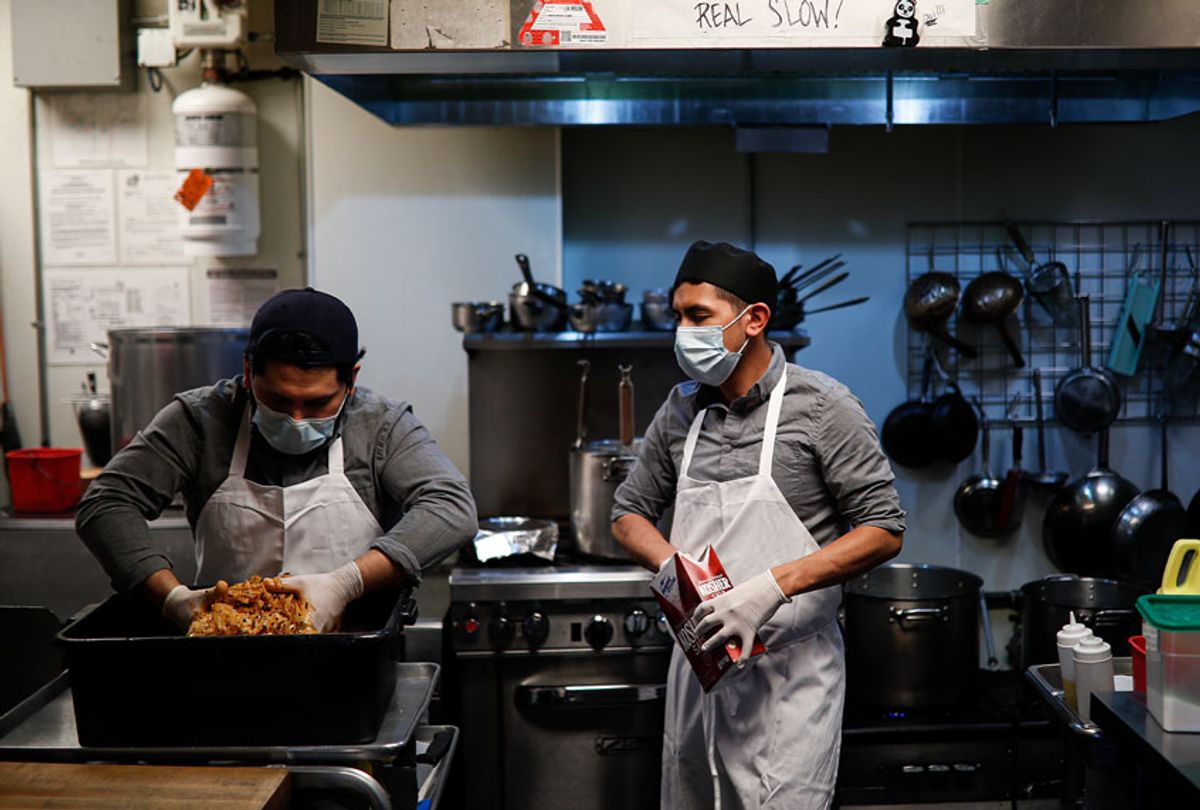 Kitchen workers wear surgical masks and gloves as they prepare food (AP Photo/John Minchillo)