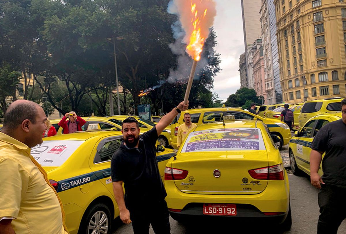 A taxi driver holds a flare during a protest in front of the Rio de Janeiro Municipal Chamber during a protest calling for the approval of a local new law (PLC 78/2018), to impose new rules for rideshare providers like Uber and 99 Taxi, in Rio de Janeiro, Brazil, on October 10, 2019.  (MAURO PIMENTEL/AFP via Getty Images)