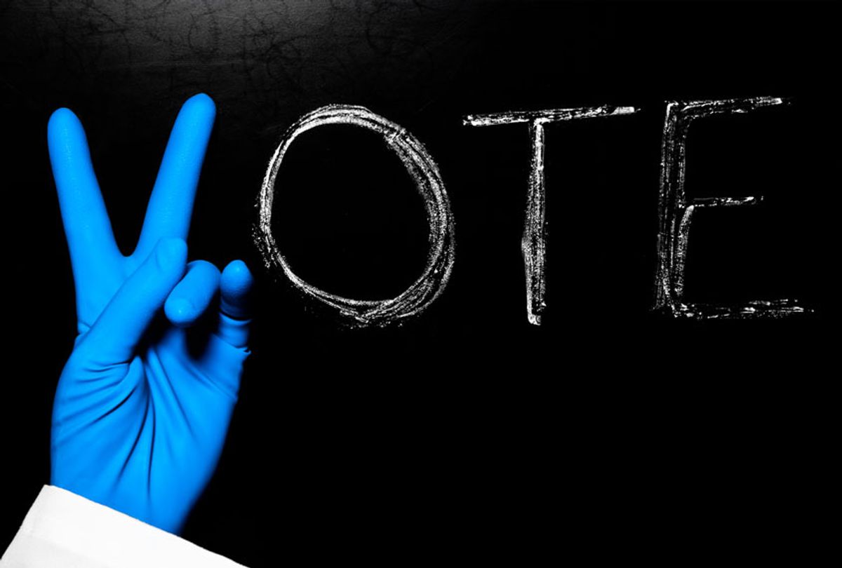 Vote on a blackboard with a blue latex-gloved human hand as the V (Getty Images)
