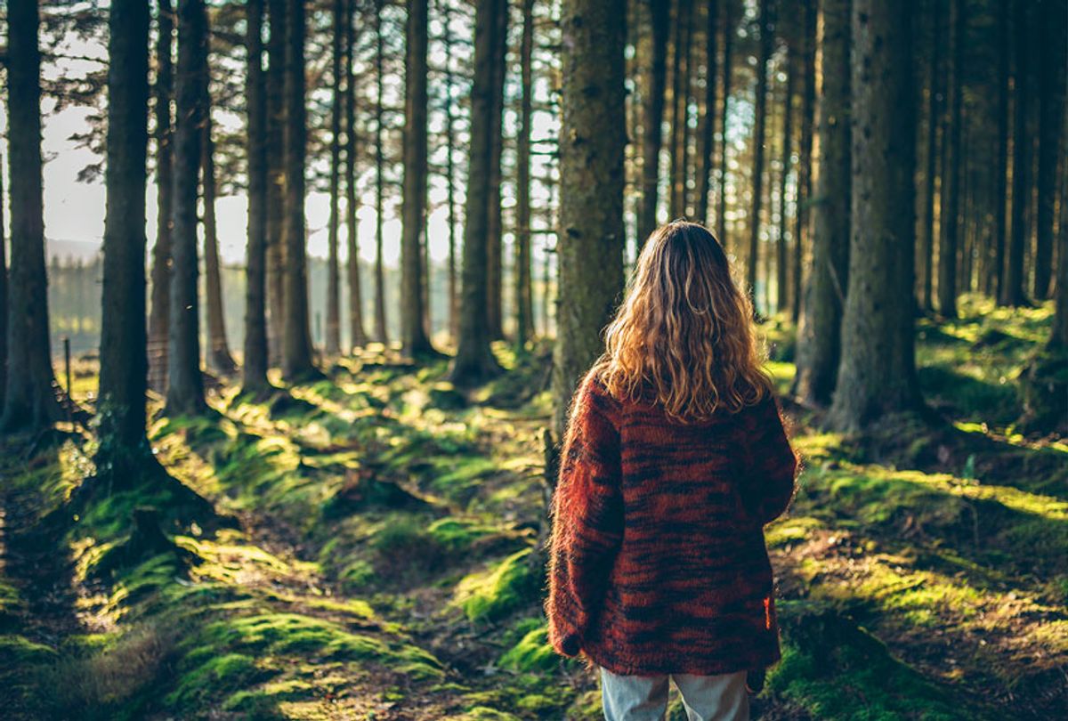 A young woman is standing in a forest at sunset (Getty Images)