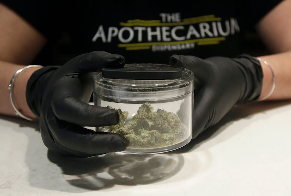 Cali Manzello, general manager at The Apothecarium cannabis dispensary, wears gloves when holding a marijuana sample for smelling while posing for photos at the store in San Francisco, Wednesday, March 18, 2020. As about 7 million people in the San Francisco Bay Area are under shelter-in-place orders, only allowed to leave their homes for crucial needs in an attempt to slow virus spread, marijuana stores remain open and are being considered "essential services." (AP Photo/Jeff Chiu)