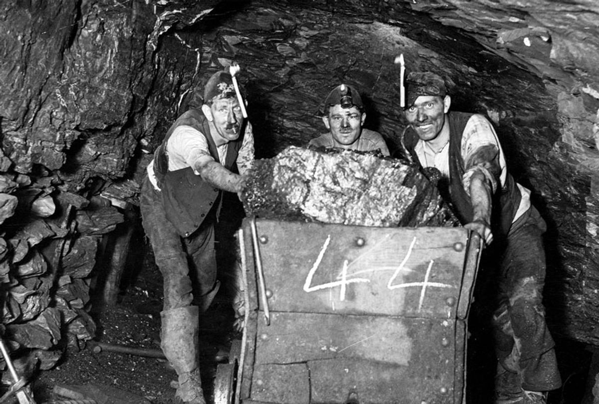 Three miners push a load of coal through the tunnel (Fox Photos/Getty Images)