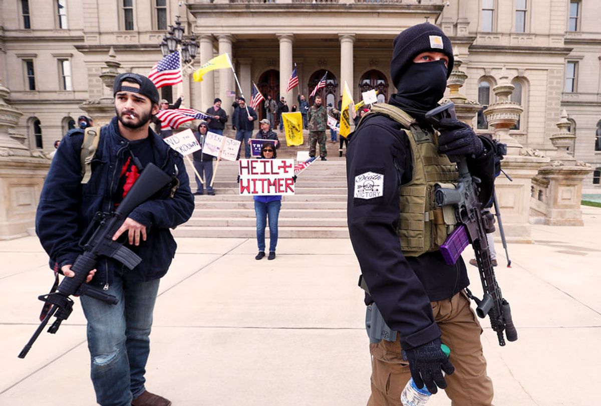 Protesters carry rifles near the steps of the Michigan State Capitol building in Lansing, Mich. (AP Photo/Paul Sancya)