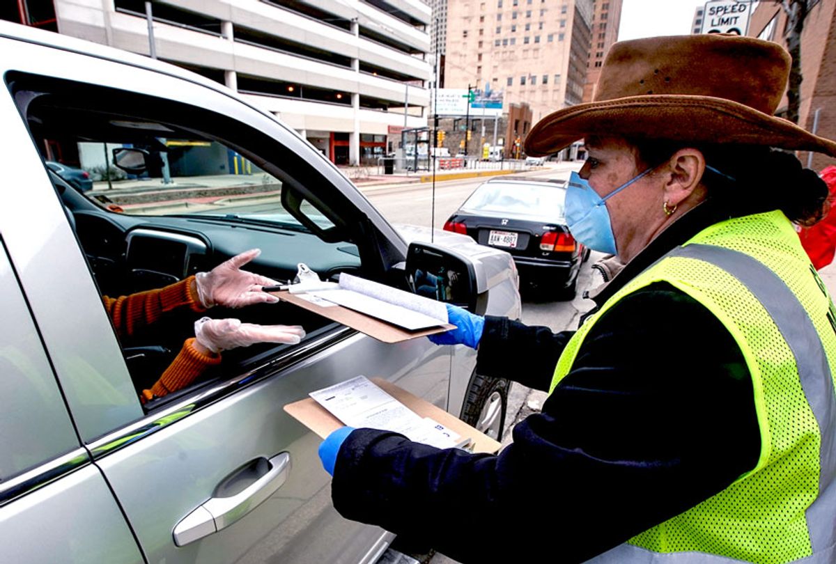 Jill Mickelson helps a drive up voter outside the Frank P. Zeidler Municipal Building Monday March 30, 2020, in Milwaukee. The city is now allowing drive up early voting for the state's April 7 election.  (AP Photo/Morry Gash)