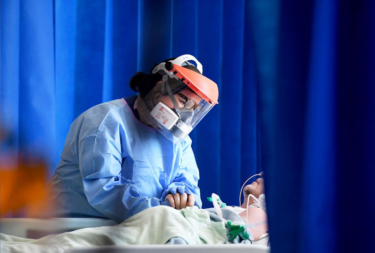 A member of the clinical staff wearing Personal Protective Equipment PPE cares for a patient with coronavirus in the intensive care unit at the Royal Papworth Hospital in Cambridge, England (Neil Hall/Pool via AP)