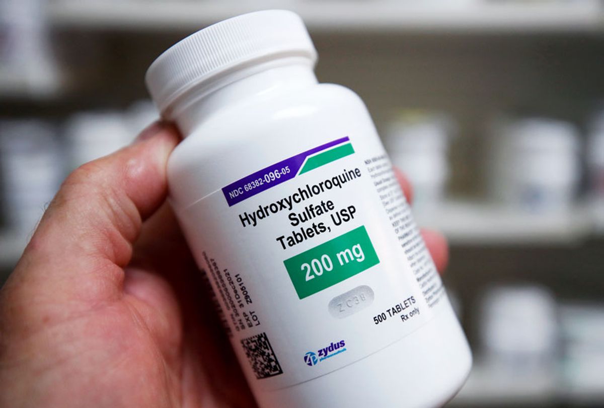 A pharmacy tech holds a bottle of Hydroxychloroquine (GEORGE FREY/AFP via Getty Images)
