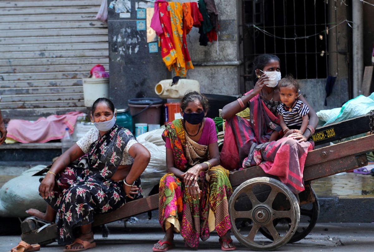 Homeless women wearing masks sit on a hand cart in Mumbai, India (AP Photo/Rafiq Maqbool)