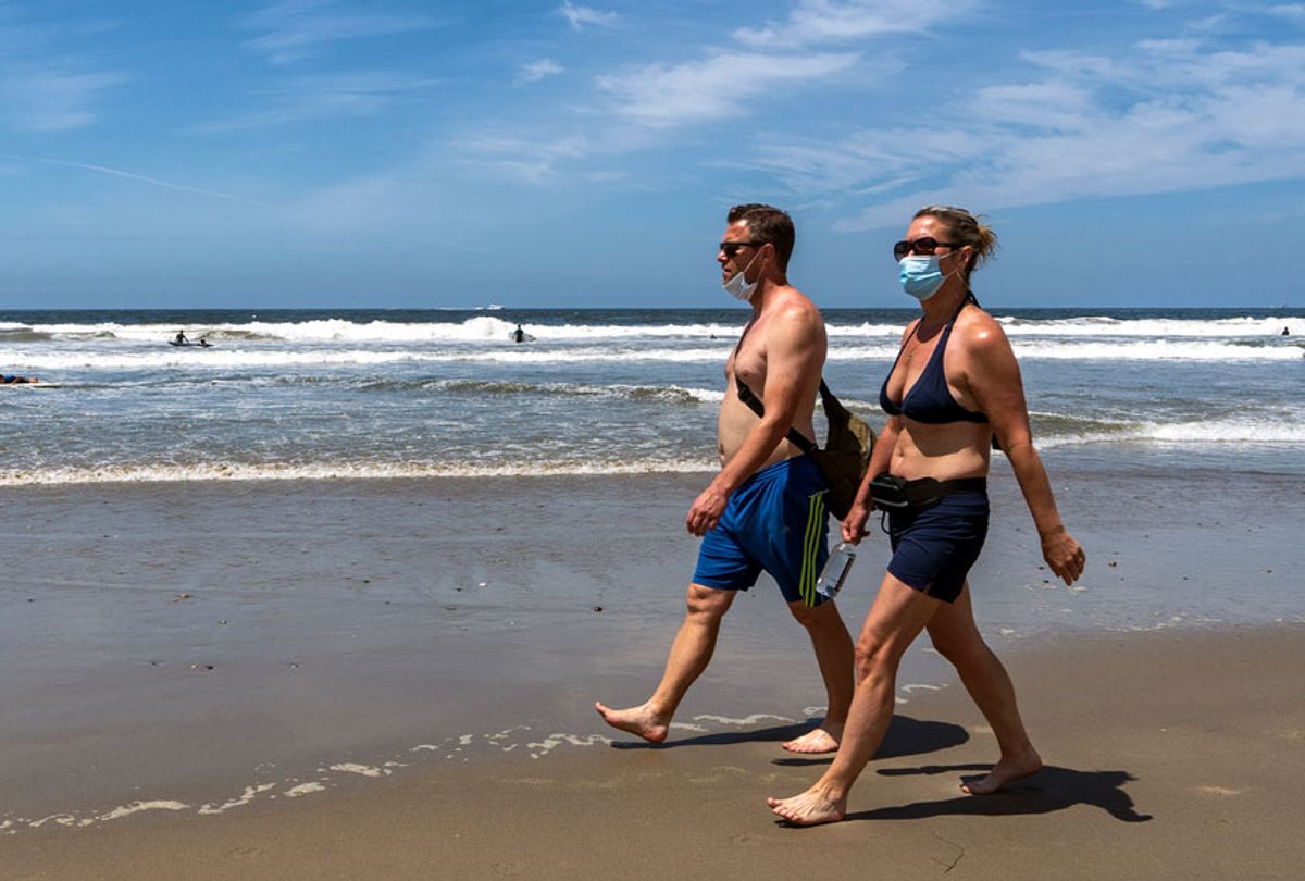 People wearing face masks as a preventive measure walk along the Venice Beach. Los Angeles County reopened its beaches for active use while requiring people to wear face masks and maintain social distancing as the county tries to reduce COVID-19 infections. (Ronen Tivony / Echoes Wire/Barcroft Media via Getty Images)