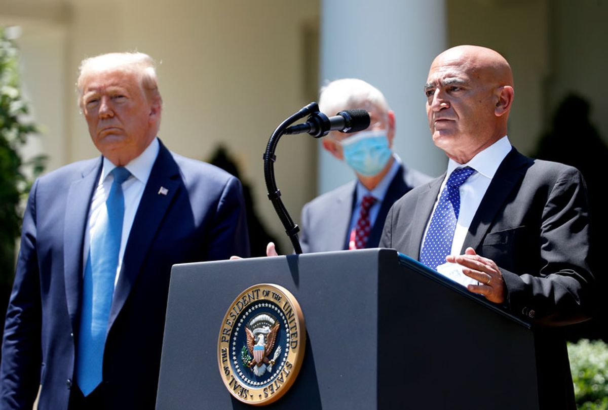 President Donald Trump, left, listens as Moncef Slaoui, a former GlaxoSmithKline executive, speaks about the coronavirus in the Rose Garden of the White House, Friday, May 15, 2020, in Washington. (AP Photo/Alex Brandon)
