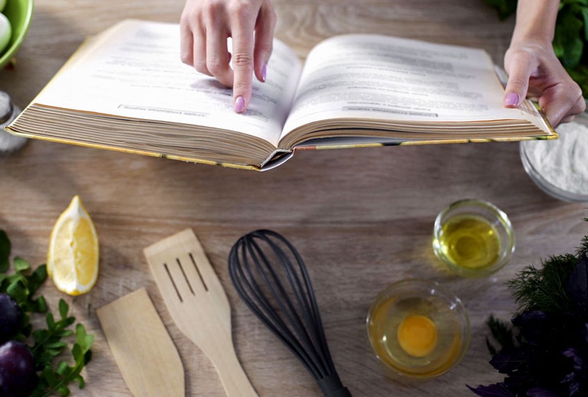Lady reading recipe in culinary book at home with kitchenware on table (Getty Images)