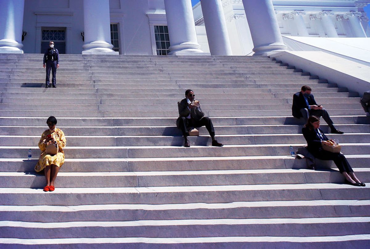 House of Delegates members eat boxed lunches at a social distance from one another on the steps of the Virginia State Capitol in Richmond, Va. (Bob Brown/Richmond Times-Dispatch via AP)