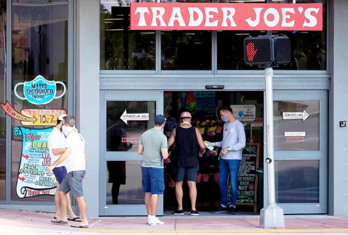 A store associate distributes hand sanitizer to customers as they enter the Trader Joe's store (Cliff Hawkins/Getty Images)