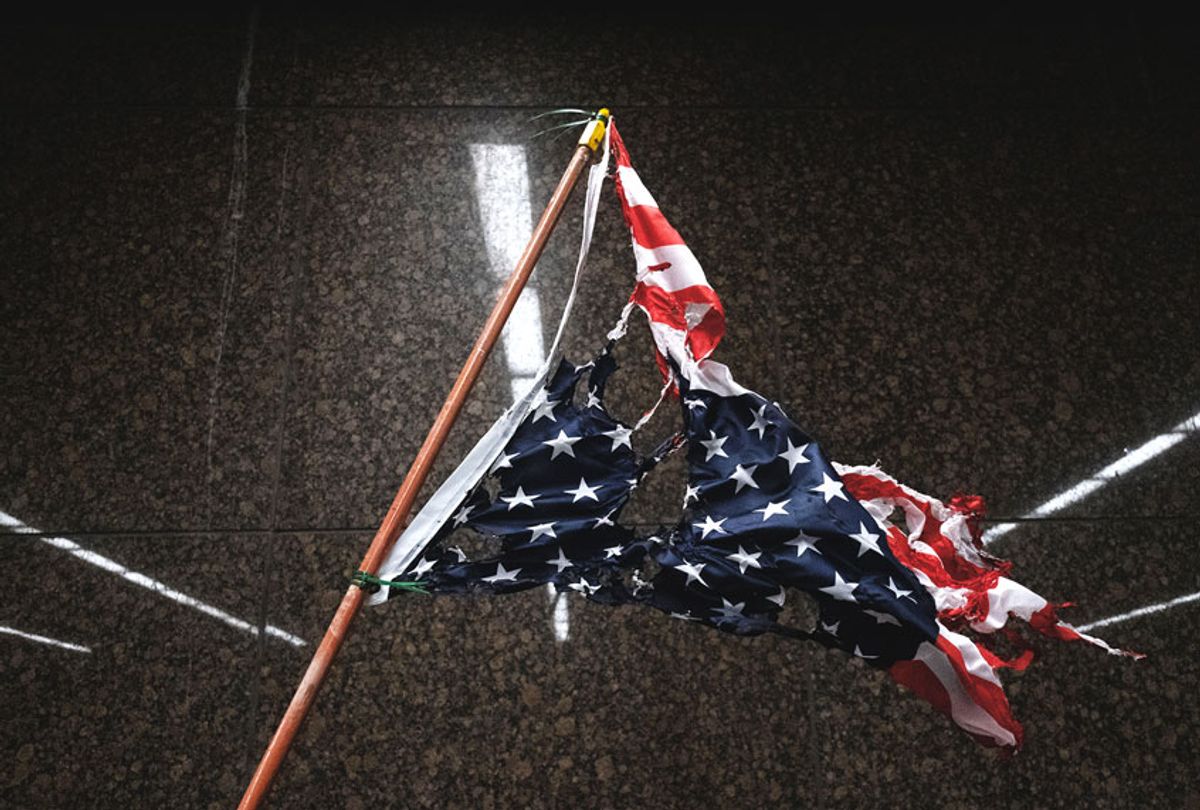 A torn and burnt upside down American flag hangs, as protesters march through the streets (SETH HERALD/AFP via Getty Images)