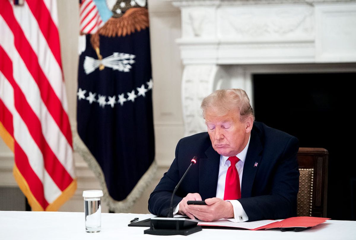 US President Donald Trump uses his cellphone as he holds a roundtable discussion with Governors about the economic reopening of closures due to COVID-19, known as coronavirus, in the State Dining Room of the White House in Washington, DC, June 18, 2020. (SAUL LOEB/AFP via Getty Images)