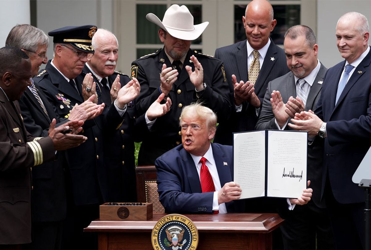 Surrounded by members of law enforcement, U.S. President Donald Trump holds up an executive order he signed on “Safe Policing for Safe Communities” during an event in the Rose Garden at the White House June 16, 2020 in Washington, DC. (Alex Wong/Getty Images)