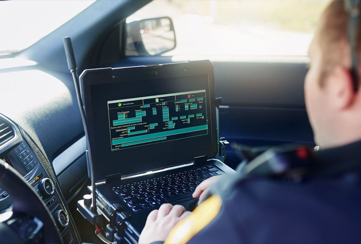 Male police officer using his laptop while out on patrol (Getty Images)