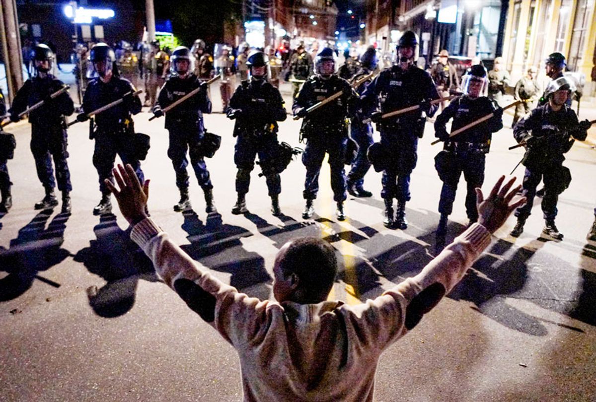A man kneels before a line of police in riot gear on Middle Street in Portland during a protest. (Gregory Rec/Portland Press Herald via Getty Images)
