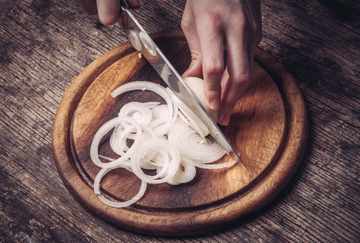 Cutting and chopping onion on wooden board with knife (Getty Images)