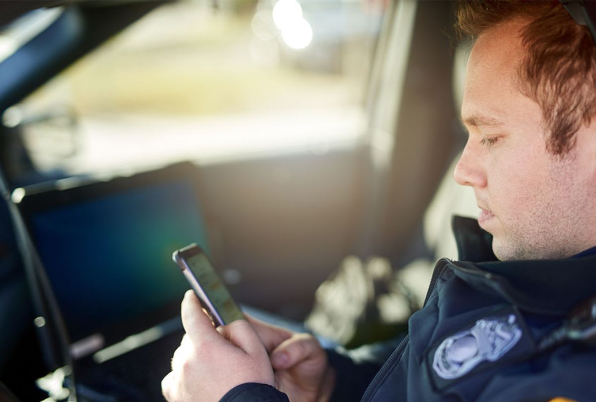 Cropped shot of a young male police officer using his cellphone while out on patrol (Getty Images)