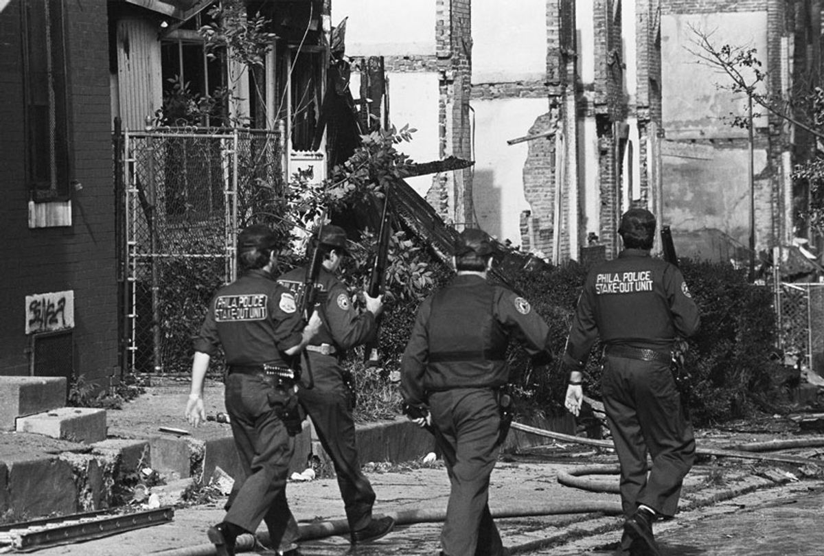 Several Philadelphia police officers stroll through the West Philadelphia neighborhood destroyed by the bombing of the MOVE headquarters. The police and radical African American organization MOVE faced off, until the police bombed the group's house. (Getty Images)