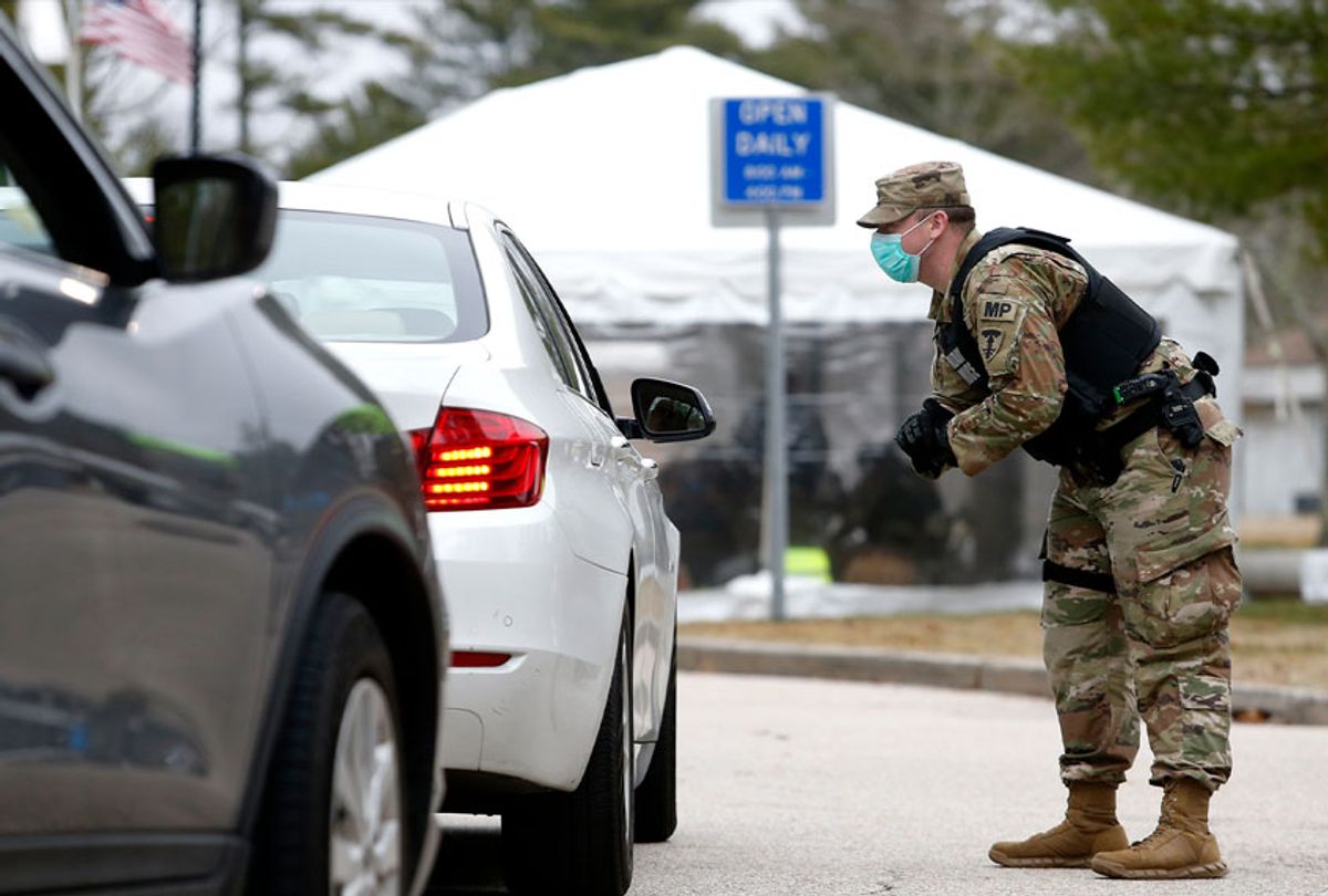 Members of the National Guard talk to out of state drivers at a checkpoint set up to hand out information to those coming in from out of state about self-quarantining for 14 days to try to reduce the spread of coronavirus on March 30, 2020 in Hope Valley, RI. Out of state drivers were directed to pull over on I-95 into a rest area between Exits 2 and 3 to speak to the National Guard. (Jessica Rinaldi/The Boston Globe via Getty Images)