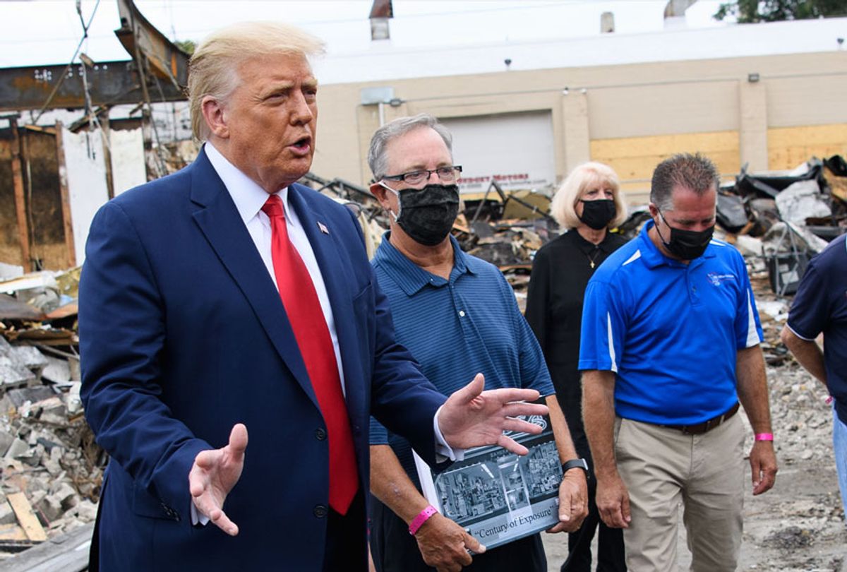 US President Donald Trump speaks to the press as he tours an area affected by civil unrest in Kenosha, Wisconsin on September 1, 2020, as John Rode(C), the former owner of the building that contained Rode's Camera Shop looks on holding a sign. (MANDEL NGAN/AFP via Getty Images)