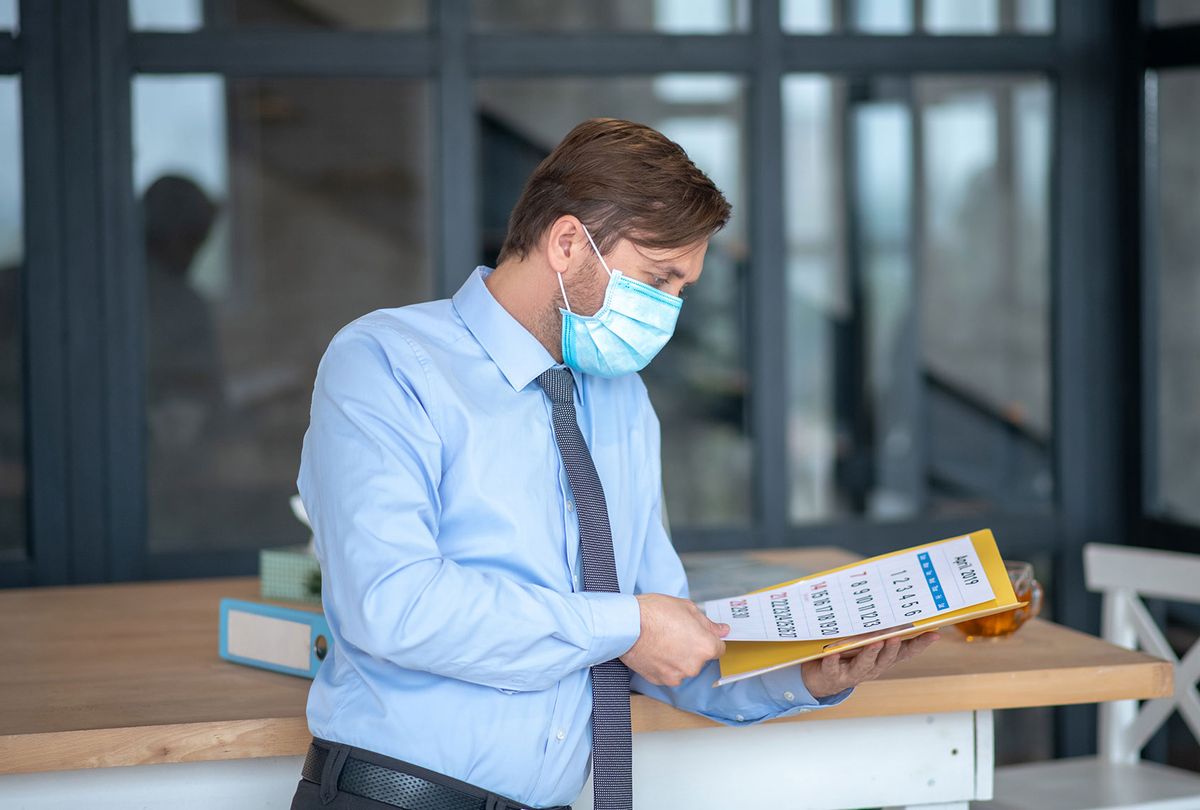 Busy businessman wearing mask checking his schedule (Getty Images)