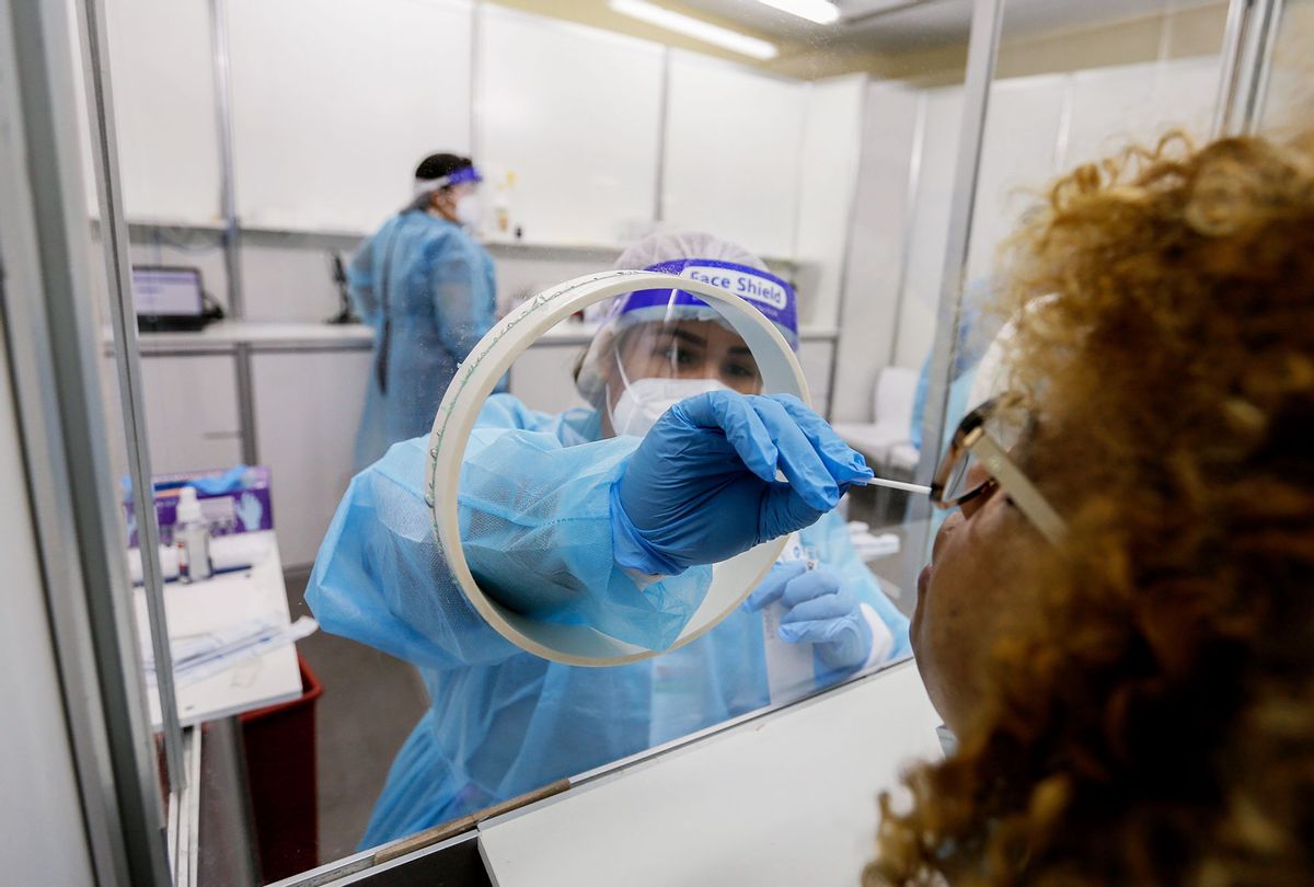 A health worker takes a swab sample from a woman at a rapid coronavirus testing station (STR/AFP via Getty Images)