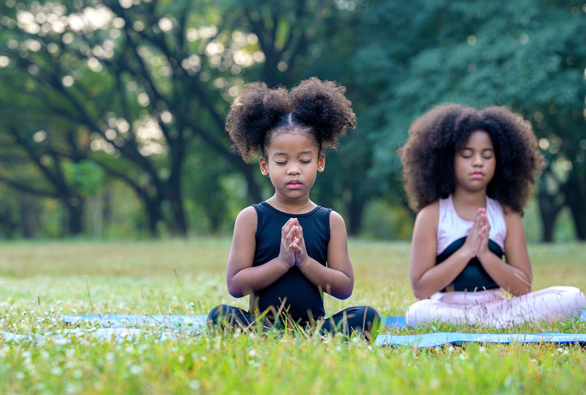 Afro American cute children in sportswear is meditating on yoga mat outdoor (Getty Images/Nitat Termmee)